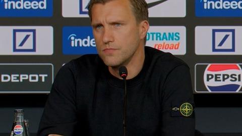 Markus Krösche sitzt bei der Pressekonferenz.