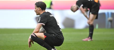 Eintracht Frankfurts Robin Koch sitzt in München enttäuscht auf dem Rasen.