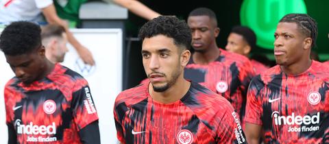 Omar Marmoush im Vordergrund. Die Eintracht-Spieler kommen zum Warmlaufen ins Wolfsburger Stadion.