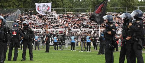 Polizisten stehen in Leipzig auf dem Rasen vor dem Fanblock von Eintracht Frankfurt