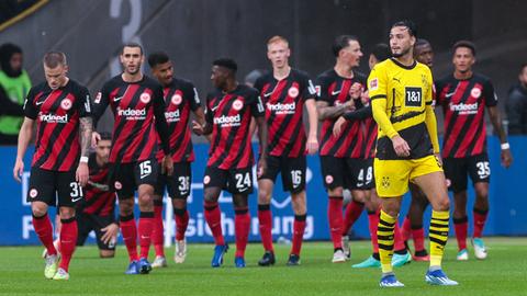 Die Eintracht-Spieler traben über den Platz, Ramy Bensebaini steht am Rand.