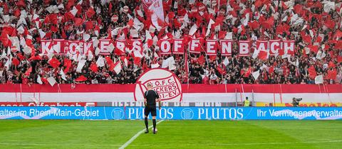 Das Bild zeigt eine Fankurve im Stadion der Kickers Offenbach. Die Zuschauer wehen rote und weiße Fahnen. 