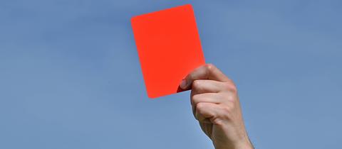 Symbolbild: Eine Hand hält eine rote Karte in die Höhe
