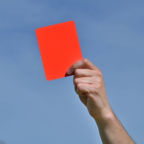 Symbolbild: Eine Hand hält eine rote Karte in die Höhe