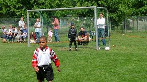 Sabiri im Kindesalter mit einem rot-weißen Trikot beim Fußballspielen.