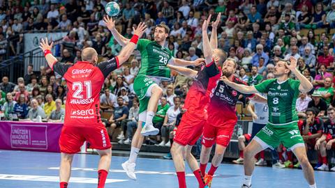 Drei Handballspieler der MT Melsungen (rote Trikots) kämpfen mit zwei Spielern der HSG Wetzlar um den Ball (grüne Trikots). 