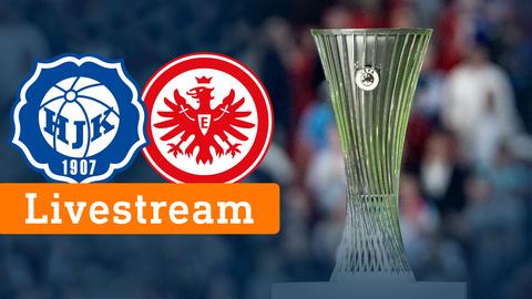 Auf einem Foto von einem Pokal ist eine orangfarbene Fläche zu sehen, auf welcher "Livestream" steht. Darüber sind zwei Logos von den Fußballvereinen Helsinki und Eintracht Frankfurt zu sehen.