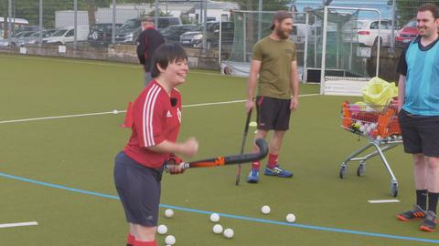 Chloé Beloin steht strahlend mit Hockeyschläger auf dem Feld.