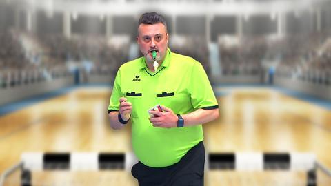 Frank Jakob in neongelber Schiedsrichter-Kleidung und mit Pfeife in dem Mund. 
