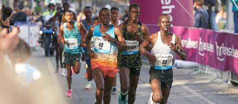 Der Kenianer Brimin Misoi (M), späterer Sieger des Marathon 2022 in Frankfurt, läuft neben Mailu Samwel Nyamai (KEN, r), und Kwambai Elkana Kibet (KEN, l) durch die Stadt.