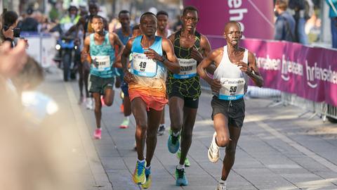 Der Kenianer Brimin Misoi (M), späterer Sieger des Marathon 2022 in Frankfurt, läuft neben Mailu Samwel Nyamai (KEN, r), und Kwambai Elkana Kibet (KEN, l) durch die Stadt.