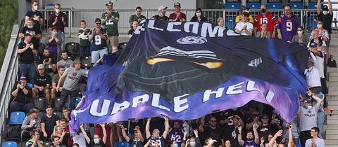 Fans der Frankfurt Galaxy halten eine Fahne mit der Aufschrift "Welcome to Purple Hell" hoch.