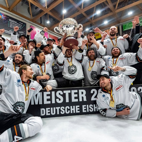 Spieler und Beteuer der Löwen Frankfurt jubeln mit dem DEL2-Pokal