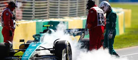 Sebastian Vettel neben seinem Formel-1-Wagen, das qualmt.