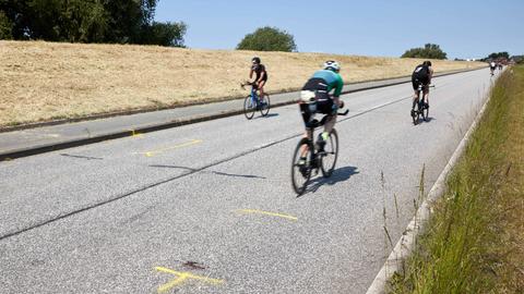 Triathleten fahren auf dem Rad an der Unglückstelle auf dem Gaueter Hauptdeich vorbei.