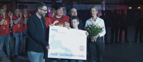 Lechleidners Tochter mit großem Schild in der Hand bei der Hallenumbenennung.