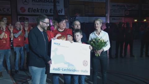 Lechleidners Tochter mit großem Schild in der Hand bei der Hallenumbenennung.