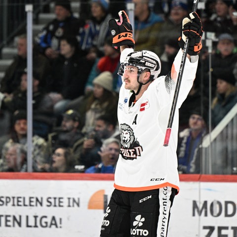 Ein Eishockeyspieler steht auf der Eisfläche und jubelt.