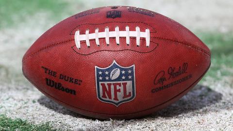 Ein Football mit dem NFL-Logo liegt auf einem Football-Feld