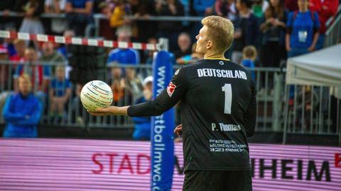 Ein Mann in einem schwarzen Trikot schlägt einen Ball auf.