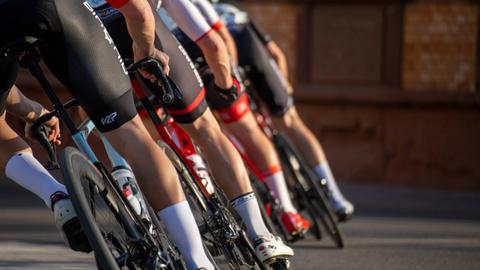 Die Beine vieler Radfahrer, die Kollone fahren, von hinten.