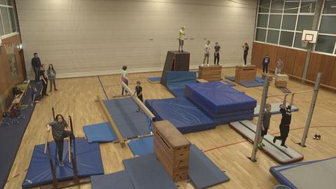 In der Turnhalle läuft das Parkour-Training. 13 Kinder klettern und springen über Hindernisse.