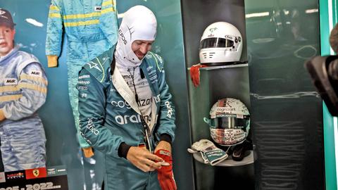 Sebastian Vettel zieht seinen Rennfahrer-Overall an und grinst