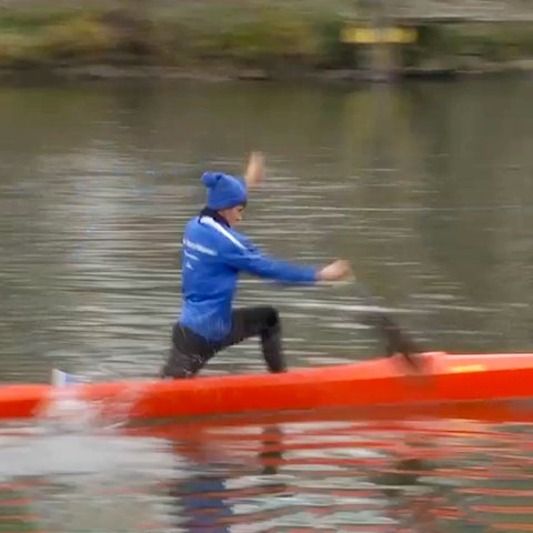 Drei Sportler in drei Booten (Renn-Canadier) nebeneinander in Fahrt auf einem Fluss - von der Seite fotografiert. 