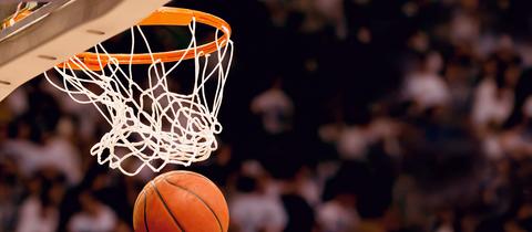 Basketball fliegt in den Korb, unscharfe Zuschauer