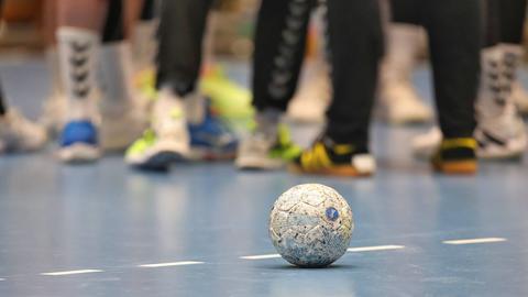 Ein Handball liegt auf dem Boden einer Sporthalle
