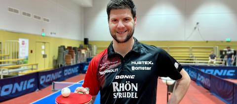 Tischtennisspieler Dimitrij Ovtcharov steht in einer Sporthalle in Fulda und lächelt in die Kamera.
