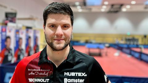 Tischtennisspieler Dimitrij Ovtcharov steht in einer Sporthalle in Fulda und lächelt in die Kamera.