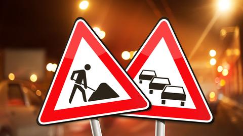 Verkehrsschilder Stau und Bauarbeiten vor diffusem Stadtlicht