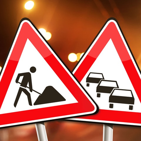 Verkehrsschilder Stau und Bauarbeiten vor diffusem Stadtlicht