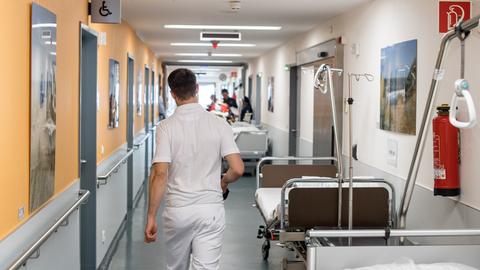 Pfleger auf einem Krankenhausflur mit mehreren Betten