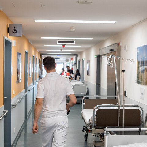 Pfleger auf einem Krankenhausflur mit mehreren Betten