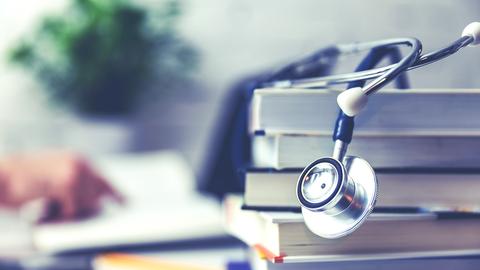 Stethoskop liegt auf Büchern im Vordergrund der Hintergrund ist unscharf