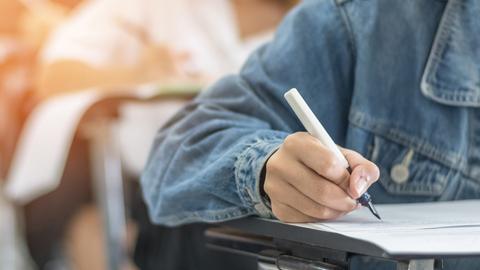 Kind mit weißem Füller in der Hand schreibt in der Schule