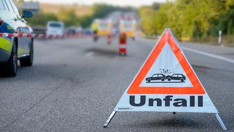Gesperrte Autobahn mit Symbol-Schild "Unfall" im Vordergrund, Absperrband und Polizeiauto