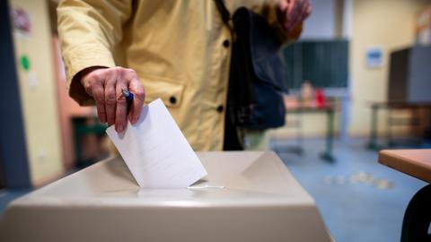 Eine Frau wirft einen Wahlschein in eine Wahlurne.