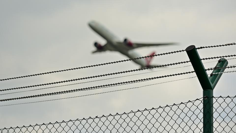 Startende Maschine am Frankfurter Flughafen hinter Stacheldrahtzaun.