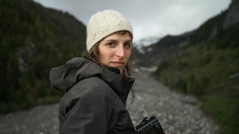 Theresa Breuer in den Bergen mit einer Kamera in der Hand.