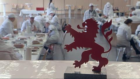 Das hessiche Wappen, im Hintergrund Fabrikarbeiter