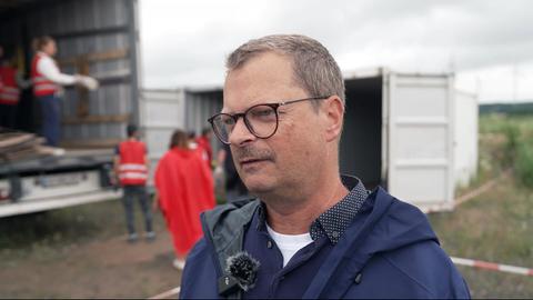Mann mit Brille. Im Hintergrund wird ein LKW beladen