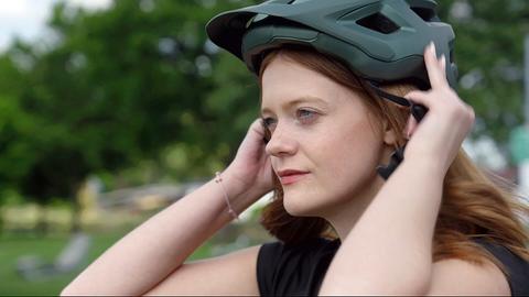 Frau zieht Fahrradhelm an