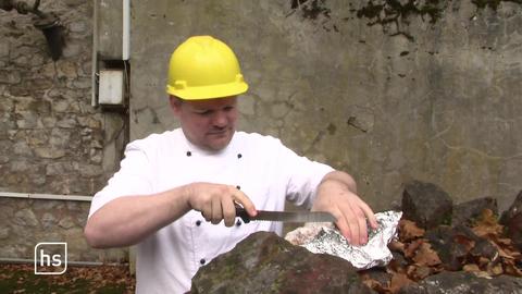 Bäcker vor Bergwerksstollen schneidet Weihnachtsstollen an.