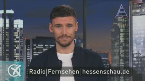 Der Moderator steht im Fernsehstudio.