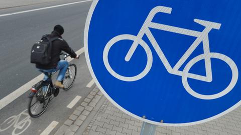 Radfahrer auf Radweg neben Radwegschild