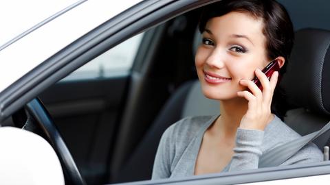 EIne Frau telefoniert im parkenden Auto mit ihrem Handy