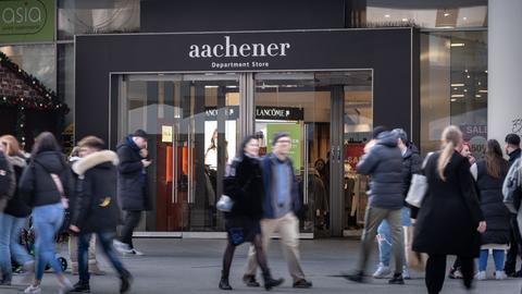 Modekette Aachener auf der Zeil - aachener Department Store steht über der Einganstür - davor laufen Menschen vorbei, die unscharf zu sehen sind. 